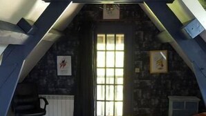 A loft bedroom with a sloped ceiling, a bed with a colorful quilt, a desk, and a chair. - Le Cottage, Country house 15 minutes from the beaches of Deauville (Saint-Julien-sur-Calonne)