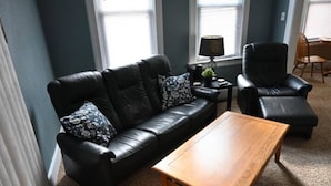 Ein Wohnzimmer mit einer schwarzen Ledersofa, einem Holztisch und einem schwarzen Ledersessel.