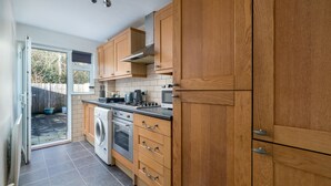 A kitchen with wooden cabinets, a washing machine, and a stove. - Crawley Pet Friendly 1-Bedroom Apartment (Crawley)