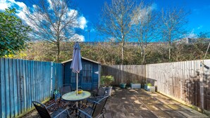 A patio with a table and chairs, a small shed, and a wooden fence. - Crawley Pet Friendly 1-Bedroom Apartment (Crawley)
