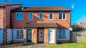 A two-story brick house with a tiled roof, a front door, and a small porch area. - Crawley Pet Friendly 1-Bedroom Apartment (Crawley)