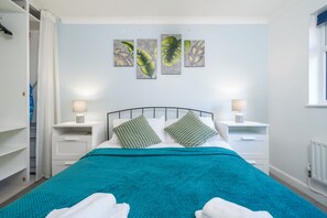 Une chambre à coucher avec un lit, deux tables de chevet avec des lampes, une fenêtre et une armoire.