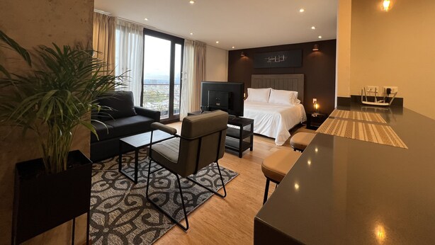 Moderni hotellihuone, jossa on suuri sänky, sohva, työpöytä ja televisio.