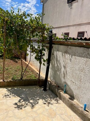 A stone-tiled patio with a wall and a small tree. - Holiday Home Lupita 2 (Posedarje)
