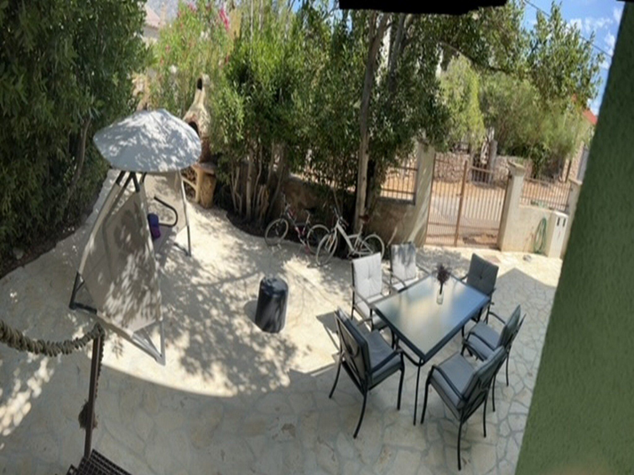 An outdoor patio with a table and chairs, surrounded by trees and a fence.