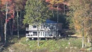 A house with a large deck, surrounded by trees with autumn foliage.
