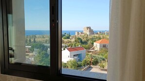 A view from a window overlooking a coastal area with historical buildings and modern structures. - Sands Hotel (Byblos)
