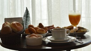 A breakfast table with bread, pastries, a cup of coffee, and a glass of juice. - Sands Hotel (Byblos)