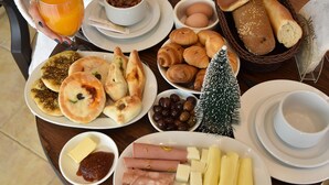 A breakfast table with various food items, including bread, pastries, eggs, and a small Christmas tree. - Sands Hotel (Byblos)
