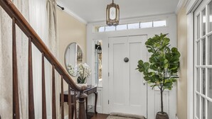 Una escalera de madera que conduce a una puerta blanca, con una planta en maceta a un lado.
