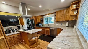Una cocina moderna con armarios de madera, un refrigerador de acero inoxidable, un microondas y un lavavajillas.