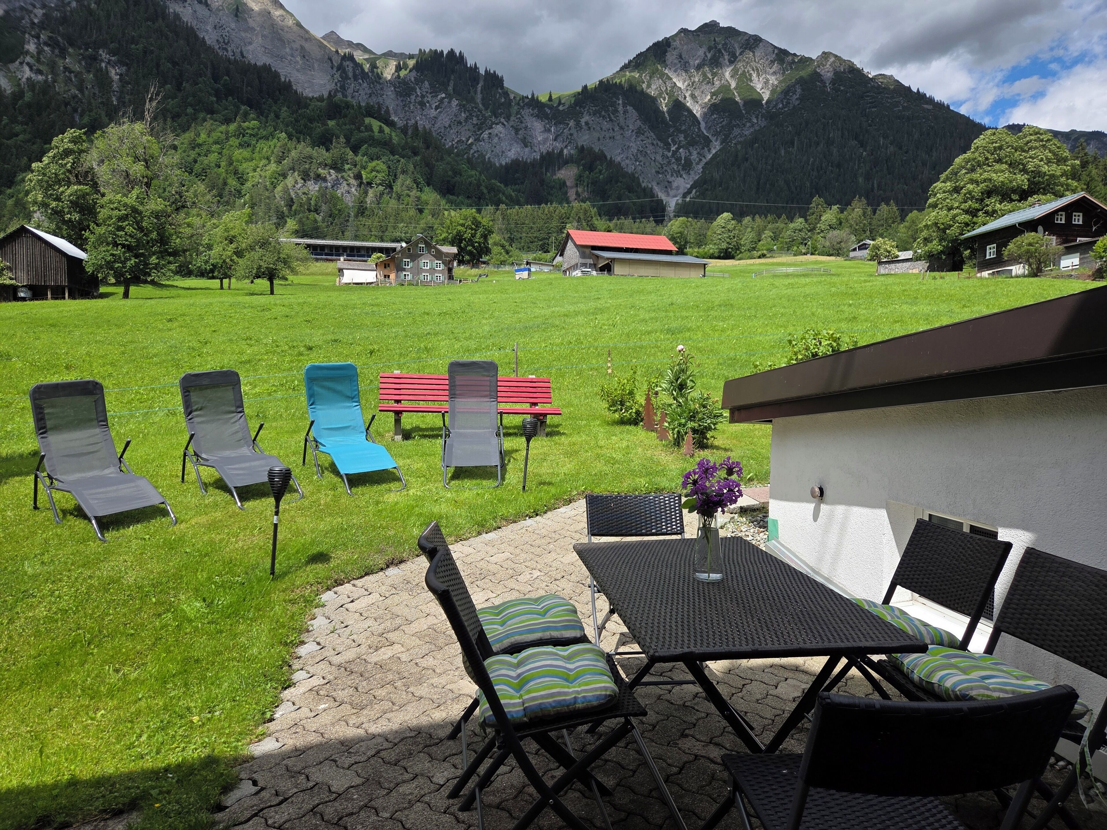 Un patio con mobiliario exterior, una mesa y vistas a un paisaje montañoso.