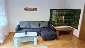 A living room with a sofa, a glass coffee table, a rug, and a green tiled wall. - Beautiful apartment on the 1st floor Top1 (Wald am Arlberg)