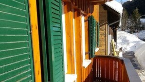 A wooden balcony with green shutters, a tiled floor, and a view of a snowy landscape. - Beautiful apartment on the 1st floor Top1 (Wald am Arlberg)