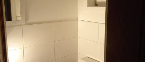 Ein kleines, weißes Badezimmer mit Toilette, Waschbecken und Spiegel.
