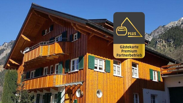 A wooden chalet with balconies, a white facade, and a mountainous backdrop. - Beautiful apartment on the 1st floor Top1 (Wald am Arlberg)