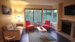 A living room with a sofa, two armchairs, a coffee table, a floor lamp, and a fireplace. - Spacious condo in downtown Bellevue (Bellevue)