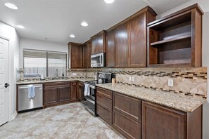 Enjoy cooking in this well-equipped kitchen with appliances, a tiled backsplash, and recessed lighting.