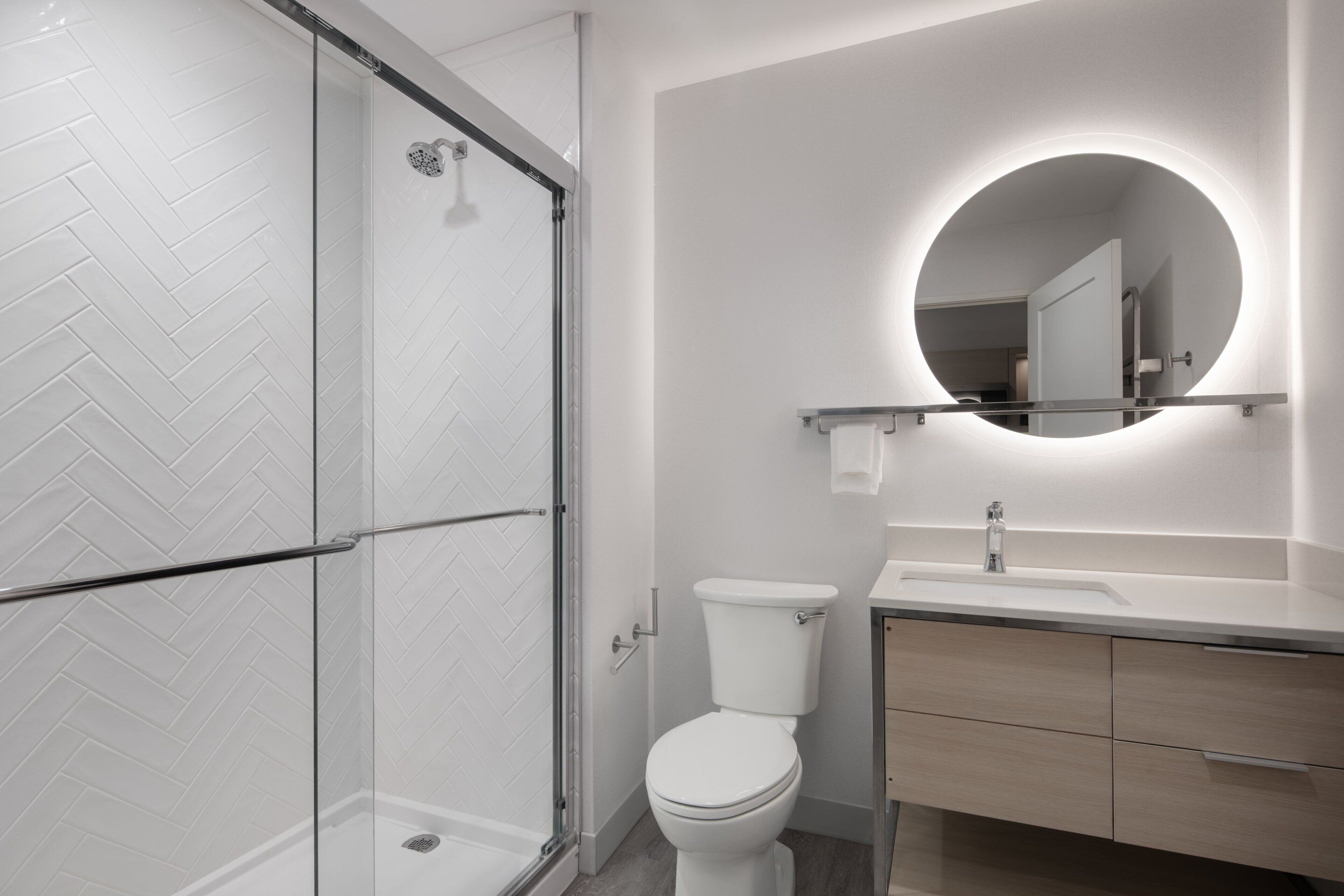 Une salle de bain moderne avec une douche à parois de verre, des toilettes et un meuble-lavabo avec un miroir.
