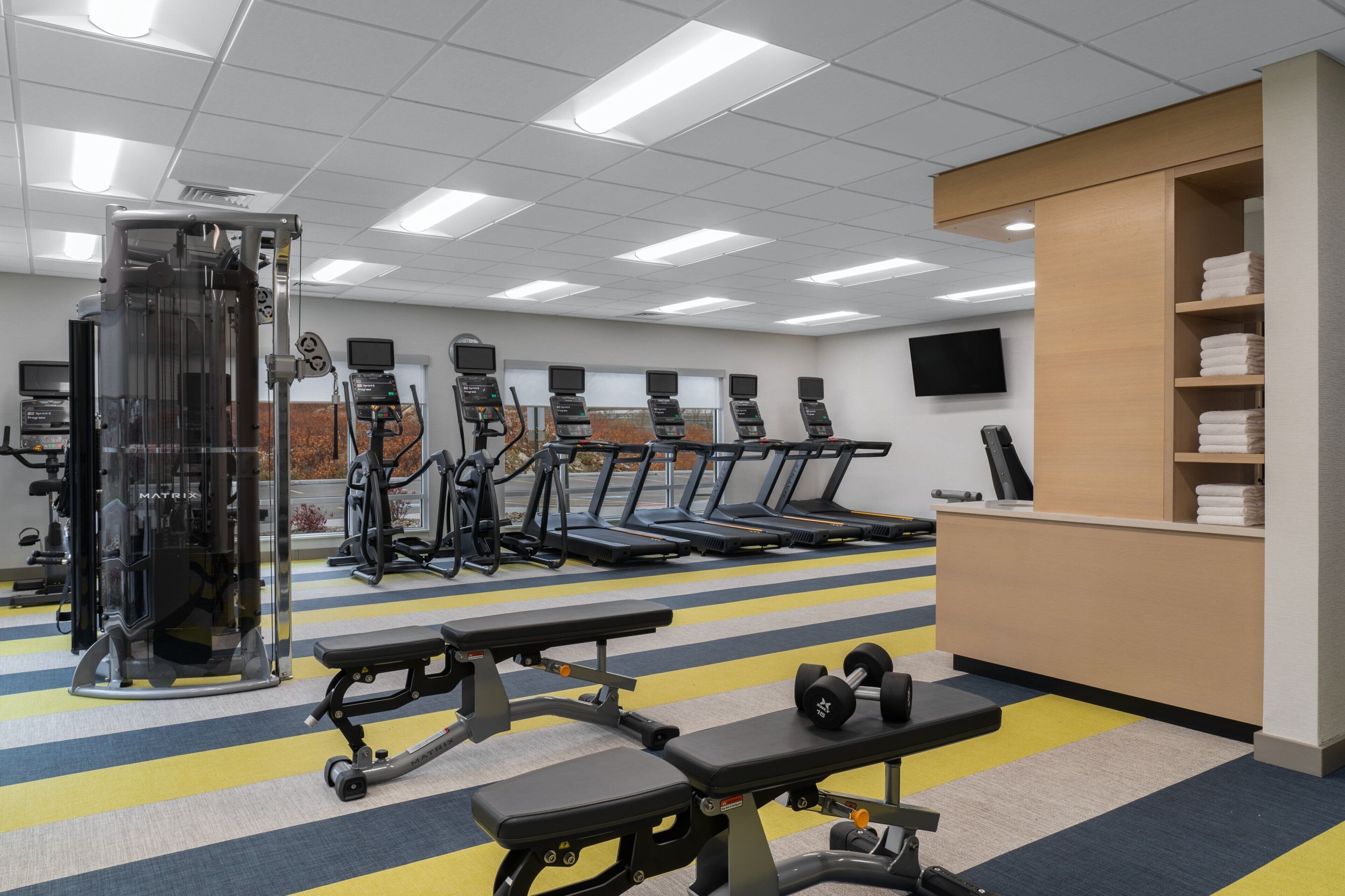 Une salle de sport équipée de tapis de course, d’appareils de musculation et d’haltères.