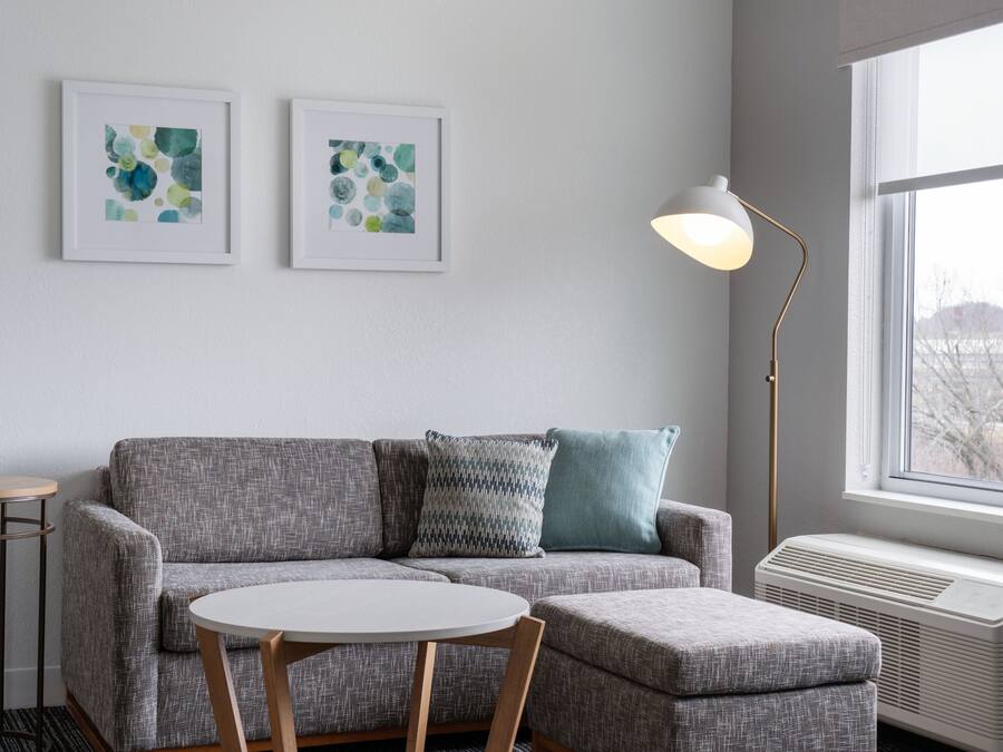 A modern living room with a grey sofa, a round white table, and two abstract art pieces on the wall.