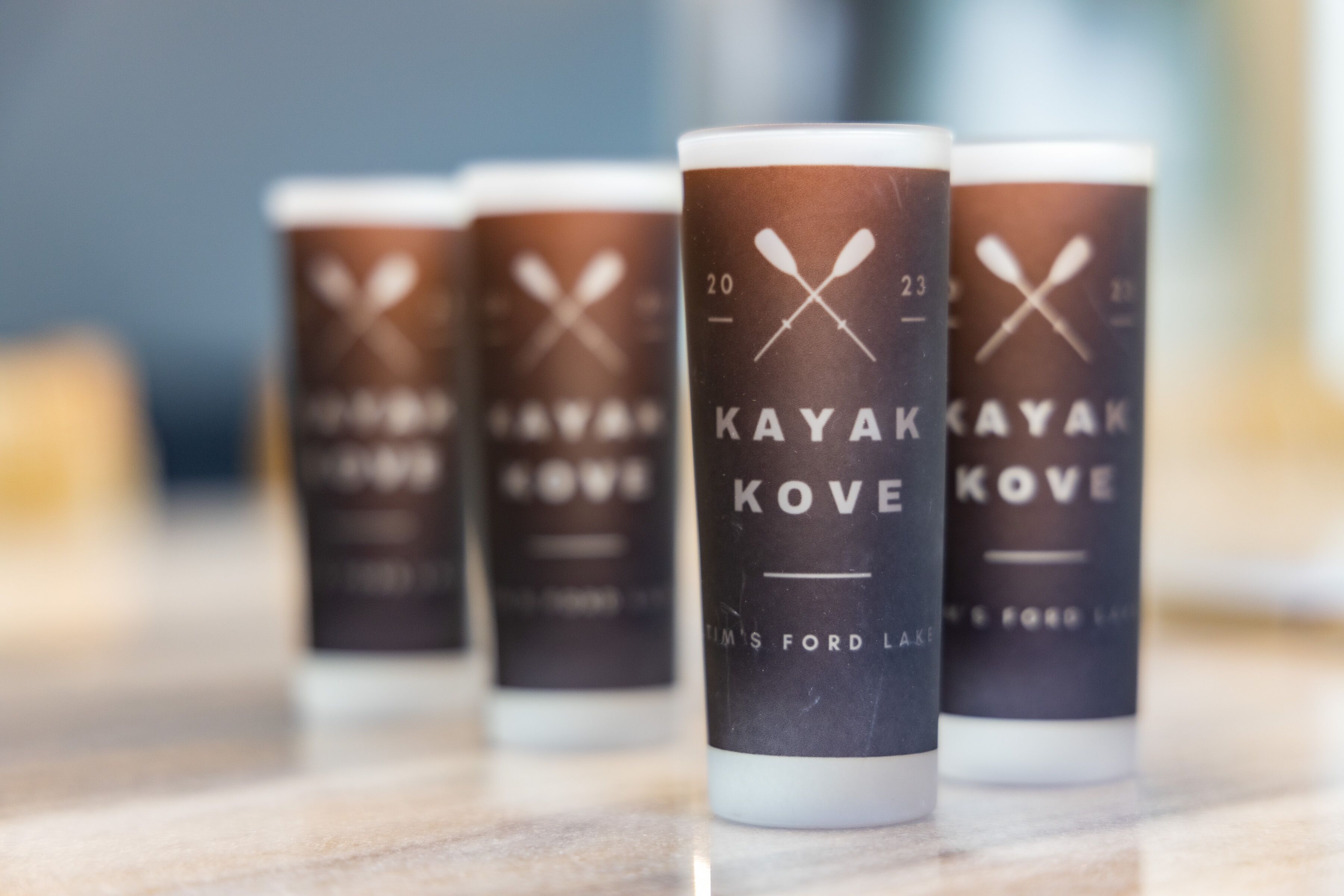 Fire flasker KAYAK KOVE øl med kajak-design på etiketten, placeret på en marmorflade.