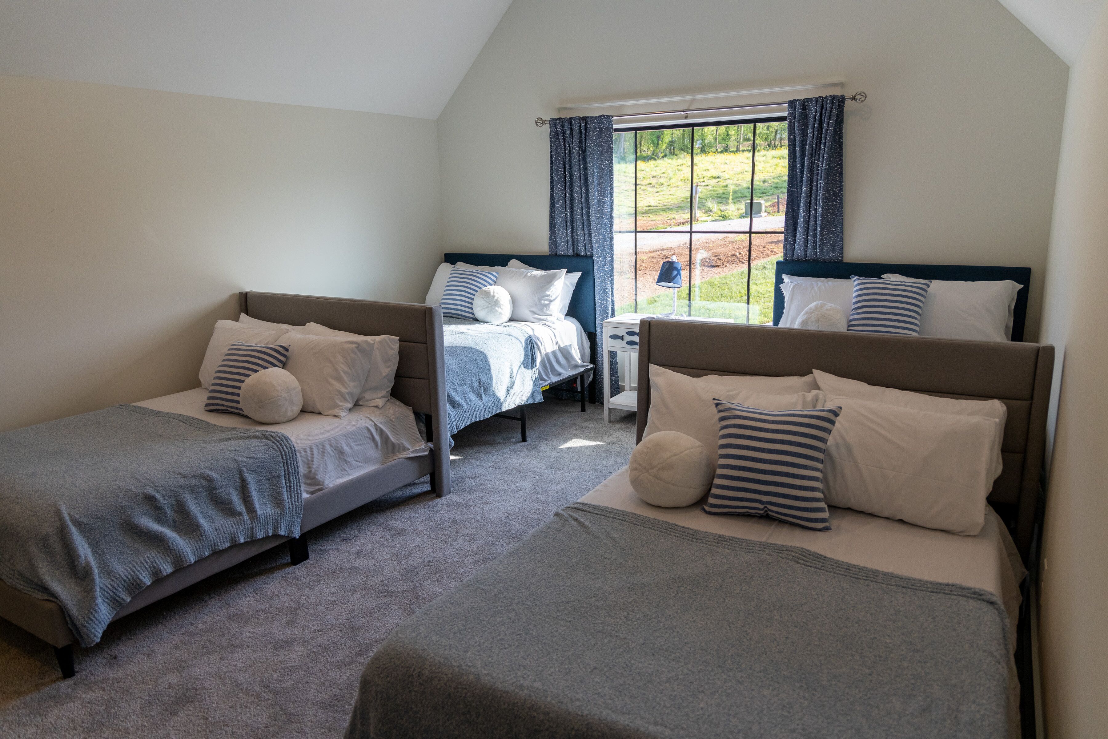 A bedroom with two single beds, a nightstand, and a window with curtains.
