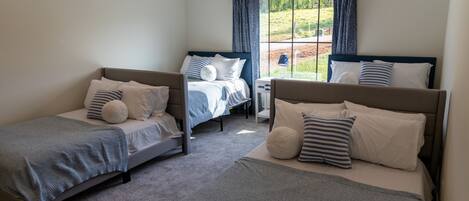 A bedroom with two single beds, a nightstand, and a window with curtains.