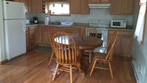 A kitchen with wooden cabinets, a refrigerator, a stove, a microwave, and a dining table with chairs. - Tea Creek Mountain Cabin (Marlinton)