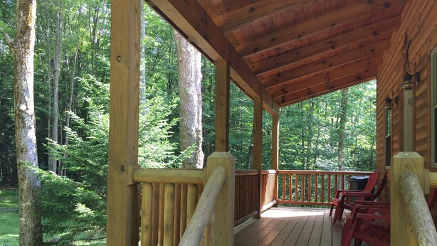 A wooden deck with a railing, surrounded by a forest. - Tea Creek Mountain Cabin (Marlinton)