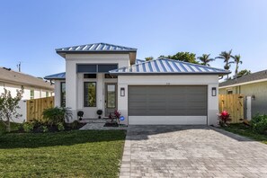 Une maison moderne à deux étages, dotée d’un garage, d’une pelouse bien entretenue et d’une allée pavée en briques.
