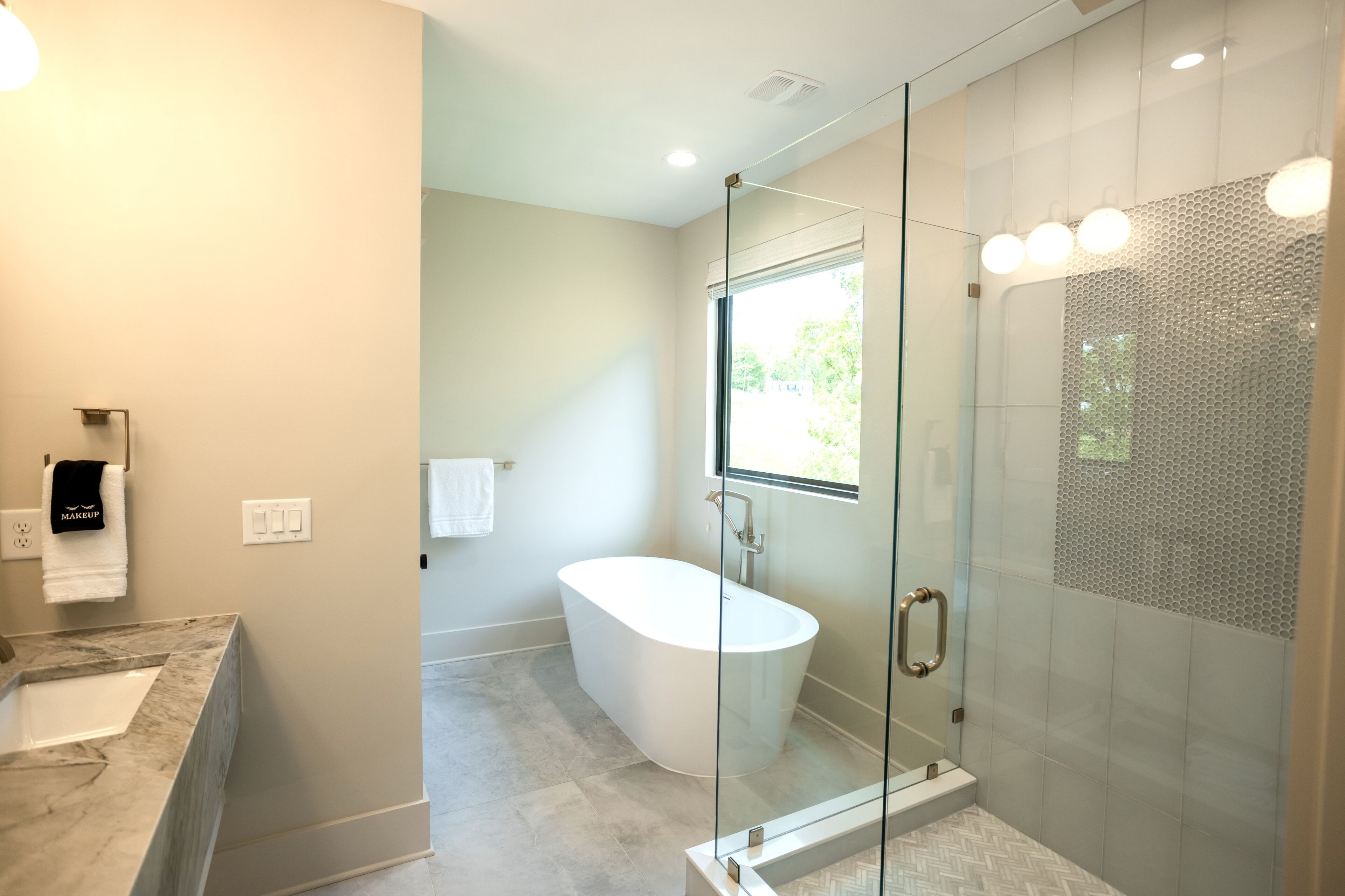 Une salle de bain moderne avec une baignoire sur pieds, une douche à parois de verre et un comptoir en marbre.
