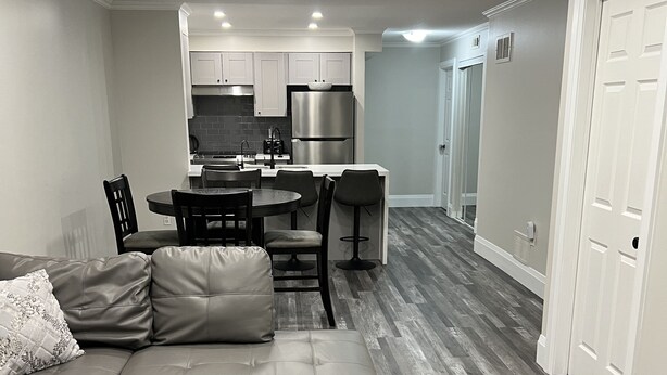 A modern living room with a sectional sofa, ottoman, and dining area with chairs. - 5 Mins from Nordic Spa Whitby (Whitby)