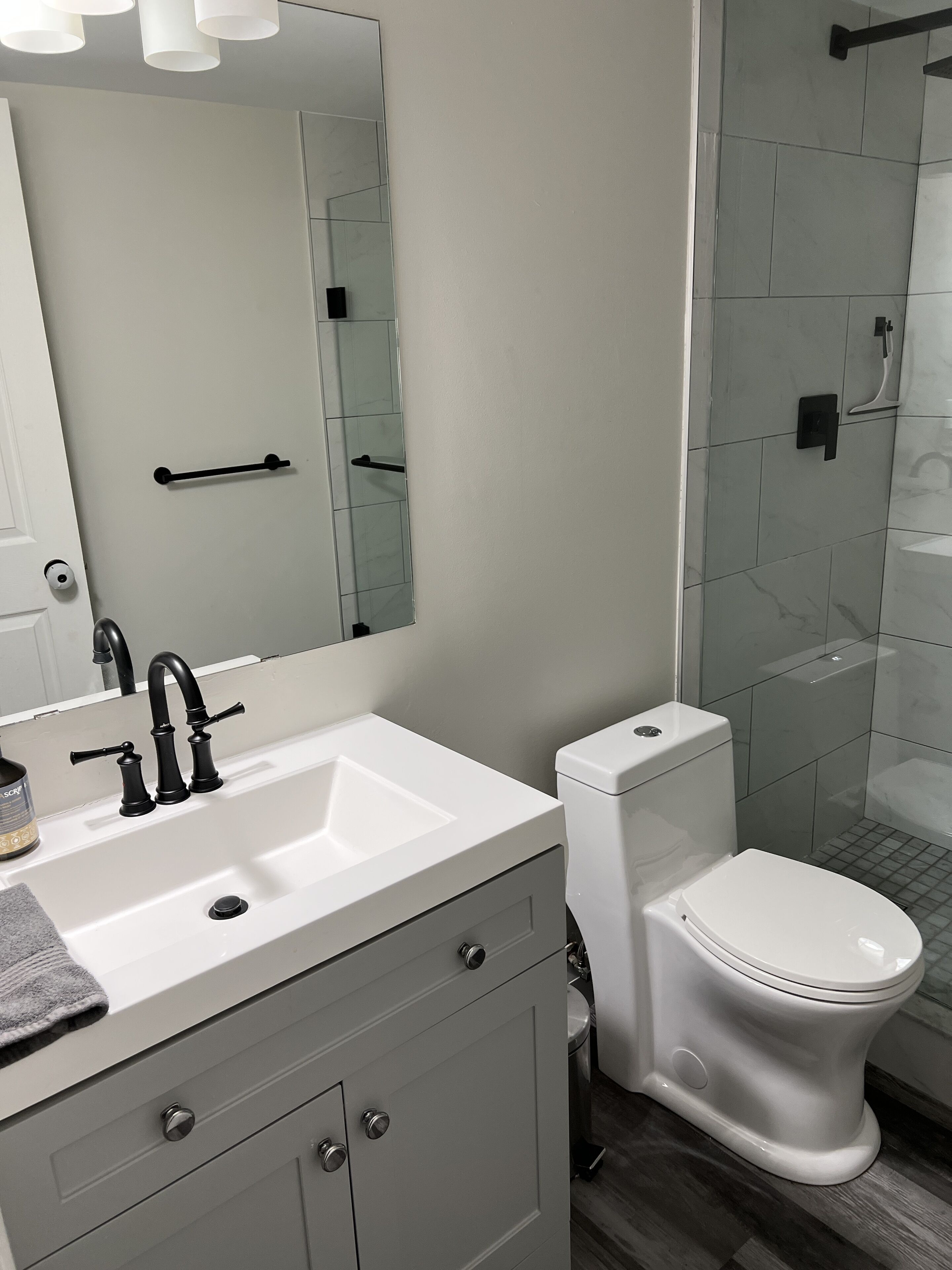 Ein modernes Badezimmer mit einem weißen Waschbecken, einem schwarzen Wasserhahn und einer Toilette.