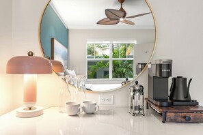 A modern kitchen with a round mirror, a ceiling fan, a coffee maker, and a coffee pot. - Corendon South Beach Miami (Miami Beach)