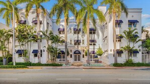 Un edificio blanco con varios balcones, palmeras y un letrero que dice "Alvin Friday's".