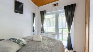 Une chambre avec un grand lit, un plafond en bois et une fenêtre avec des rideaux.