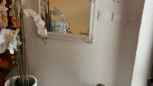 Une salle de bain avec un lavabo blanc, un miroir doté d’un cadre orné et une plante orchidée en pot.