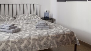 Een slaapkamer met een bed, een nachtkastje, een lamp en een lijst met een afbeelding aan de muur.