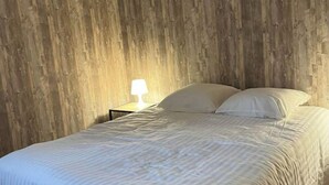 A bedroom with a bed, a nightstand, and a lamp.