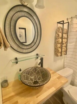 Bathroom features a round mirror, wooden vanity, and patterned sink.