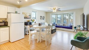 Una cocina moderna con armarios blancos, un refrigerador y un comedor con una mesa y sillas blancas.