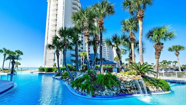 A hotel with a pool surrounded by palm trees and a waterfall feature. - Edie's Escape-Long Beach 501T3-3BD/3BTH End Unit-2 Sets of Beach Chairs Included! (Panama City Beach)