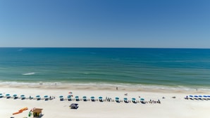 A beach with rows of blue umbrellas and lounge chairs, a lifeguard tower, and a clear view of the ocean. - Edie's Escape-Long Beach 501T3-3BD/3BTH End Unit-2 Sets of Beach Chairs Included! (Panama City Beach)