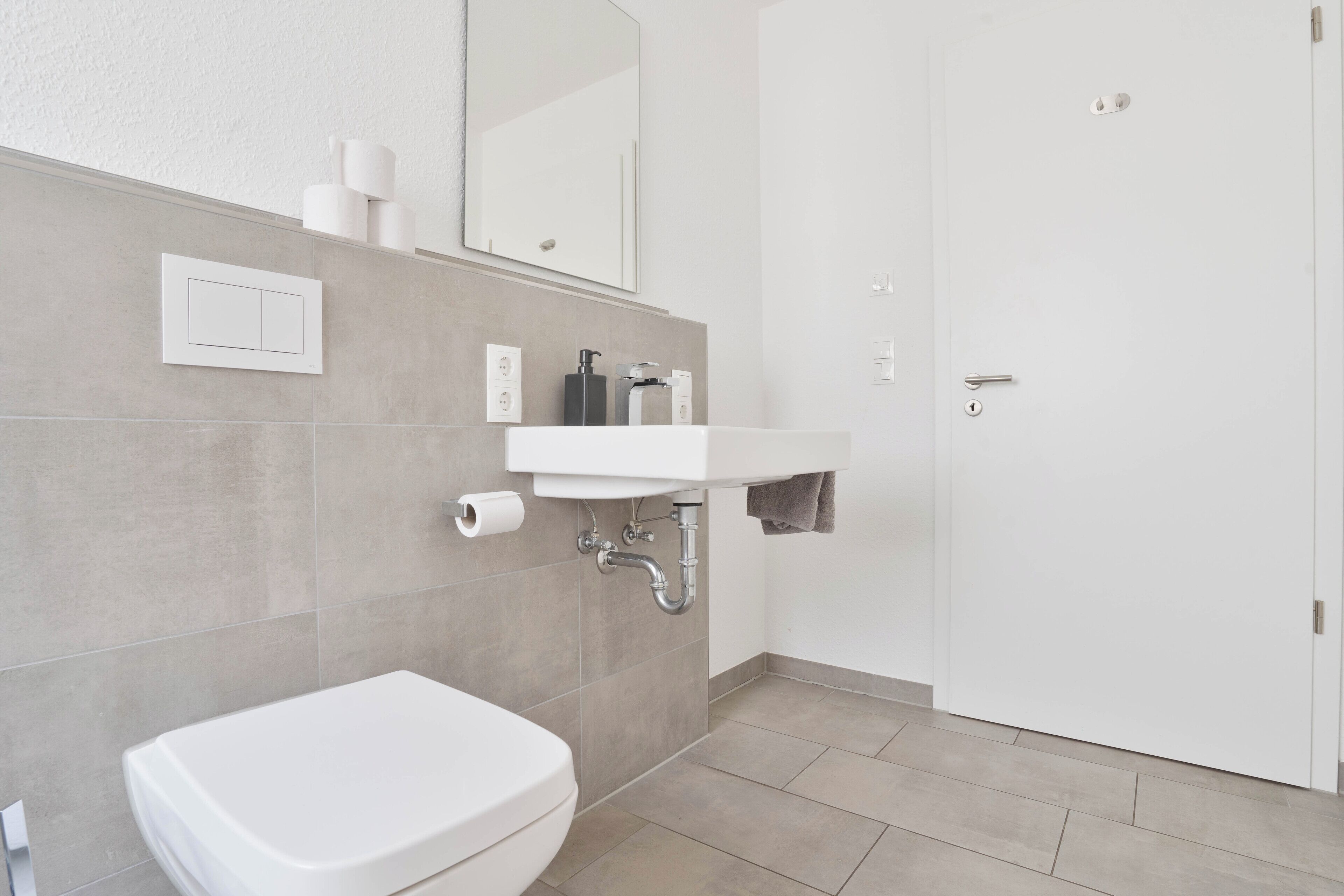 A modern bathroom with a white toilet, a sink, and a mirror.