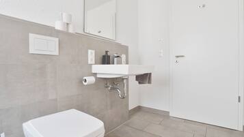 A modern bathroom with a white toilet, a sink, and a mirror.