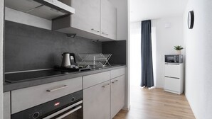A modern kitchen with grey cabinets, a black countertop, and a built-in oven. - Deluxe apartment in the centre of OS (Osnabrueck)