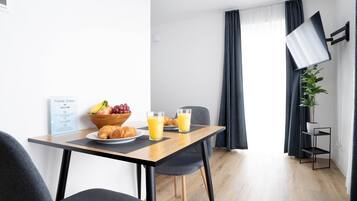 Una habitación de hotel moderna con una mesa de comedor de madera, dos sillas, un cuenco de fruta y dos vasos de jugo de naranja.