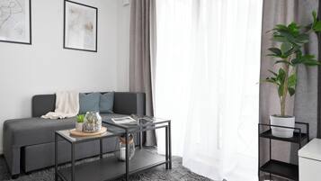 Un salon moderne avec un canapé gris, une table basse en verre et une plante en pot.
