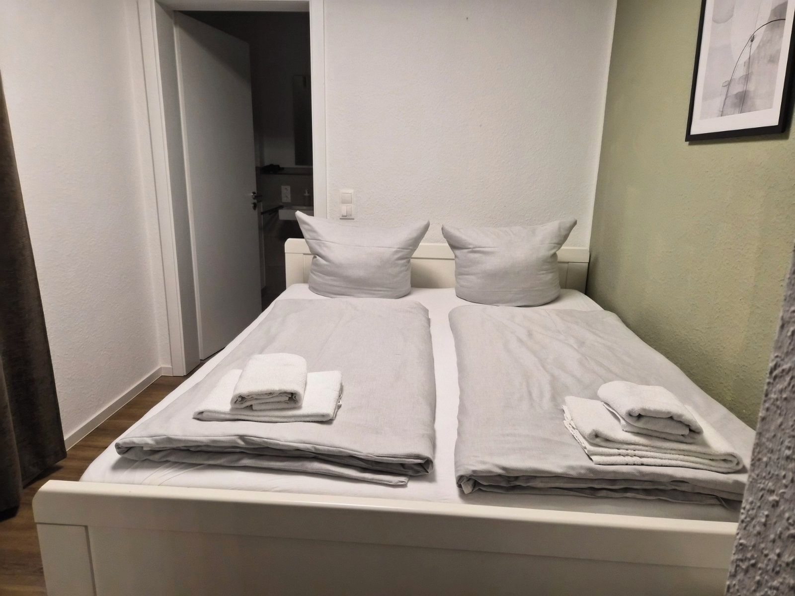 A hotel room with a bed, pillows, and folded towels.